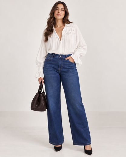 A plus size curvy woman modeling a high-waisted, wide-leg blue jeans.